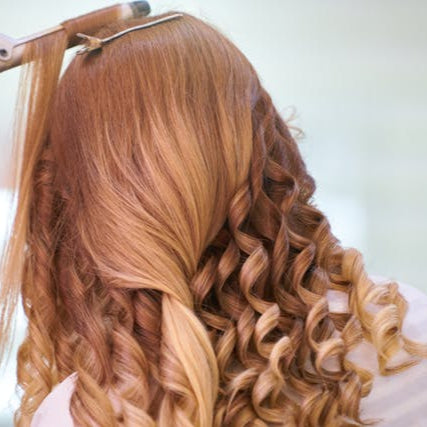 Hairstylist creating curls with a curling iron at Tru Hair Studio in Brighton, CO, offering styling for special events.