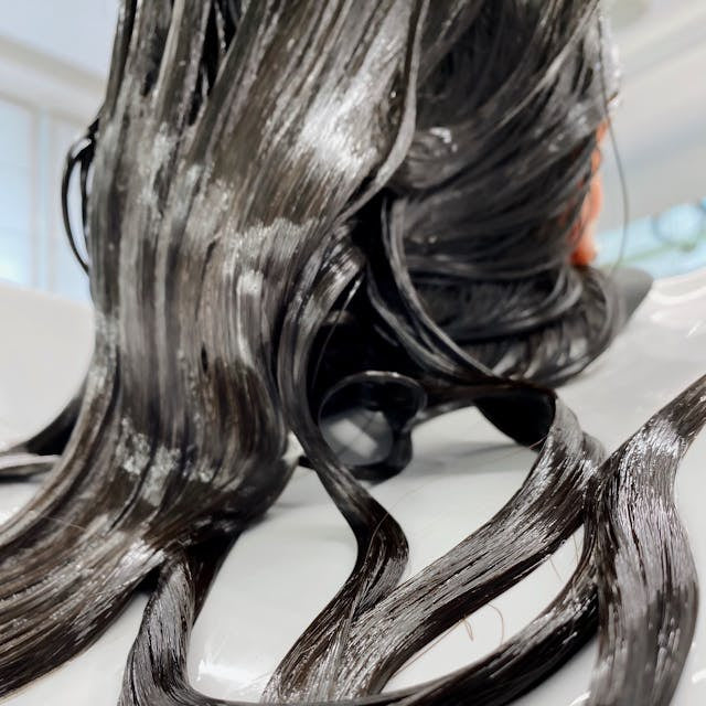 Close-up of nourishing deep conditioning treatment applied to wet hair at Tru Hair Studio in Brighton, Colorado.
