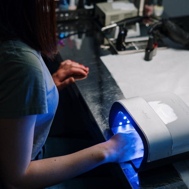 Client curing gel polish under a UV lamp at Tru Hair Studio Nail Salon in Brighton, Colorado.