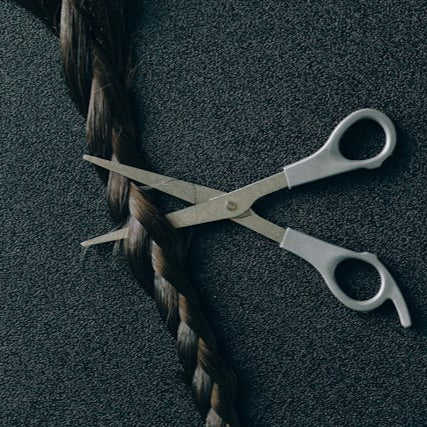 Close-up of scissors cutting a braid, representing hairstyling, braid care, and maintenance services at Tru Hair Studio in Brighton, CO.