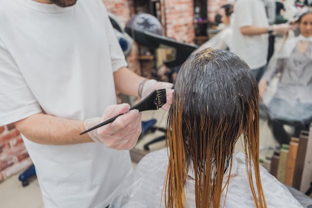 Stylist applying professional hair dye to a client’s hair at Tru Hair Studio in Brighton, Colorado.
