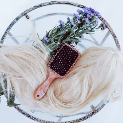 Professional hair extensions with styling brush and floral decor, representing Tru Hair Studio’s hairstylist services in Brighton, CO.