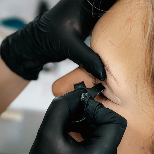 Stylist shaping brows with precision tools after waxing at Tru Hair Studio in Brighton, Colorado