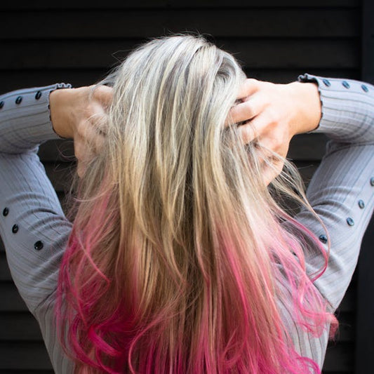 Woman with blonde hair and vibrant pink ombre coloring at Tru Hair Studio in Brighton, Colorado, showcasing professional hair color services.