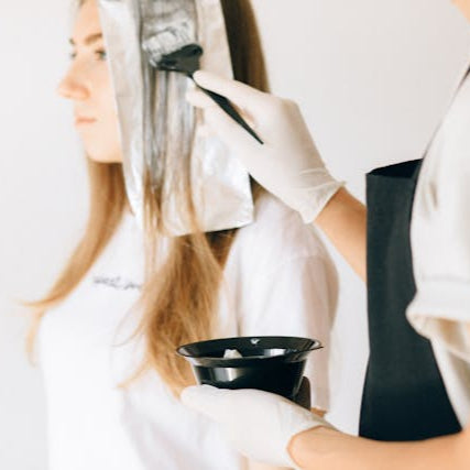 Stylist applying foil highlights and hair color to a client’s hair at Tru Hair Studio in Brighton, Colorado, offering women’s hair coloring and styling services.
