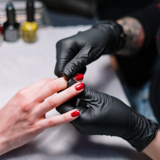 Nail technician applying glossy red polish during a manicure at Tru Hair Studio Nail Salon in Brighton, CO.